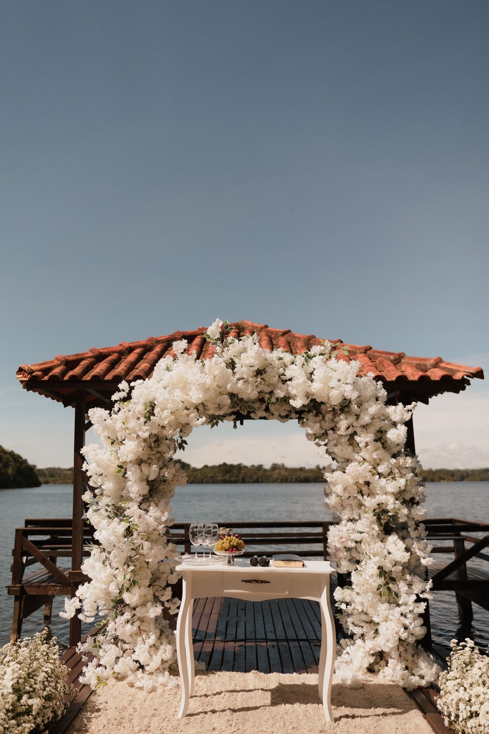 A white floral arch by the water set for a ceremony